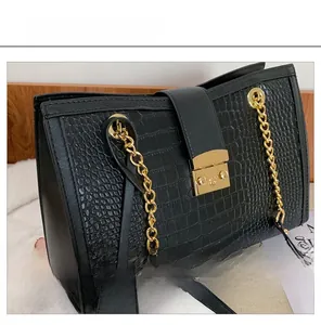 Close-up of black crocodile embossed texture with elegant gold metal lock and chain strap