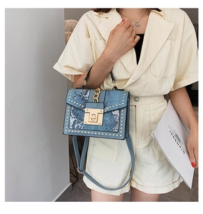 Detail showing blue snakeskin handbag with gold rivets and metallic square lock closure
