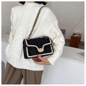 Détail du sac à bandoulière en tweed noir avec chaîne dorée et fermoir rotatif élégant
