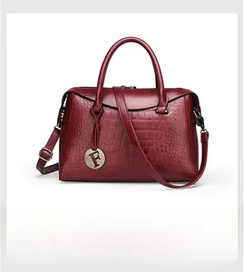 Close-up of wine red crocodile embossed leather handbag with metal F pendant