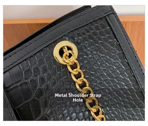 Macro shot of black crocodile embossed leather texture with golden metal eyelet and chain