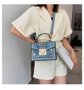 Blue snakeskin pattern handbag with gold studs and chain handle shown with model