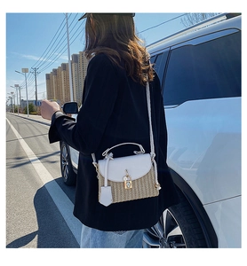 Detail of woven straw crossbody bag with white leather flap and metal square lock closure
