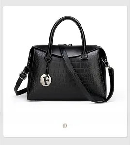 Detailed view of crocodile embossed Boston bag with silver round F pendant and handles