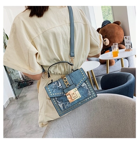 Blue snakeskin embossed crossbody bag with gold studs and metal chain detail on model