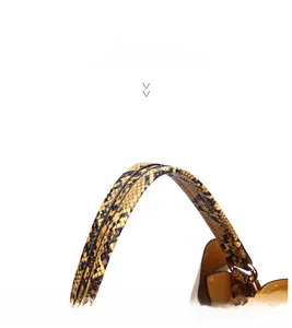 Detail of yellow snake skin pattern handbag with ergonomic handle and metal buckle