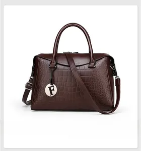 Detail of dark brown crocodile pattern Boston bag with circular F silver metal pendant