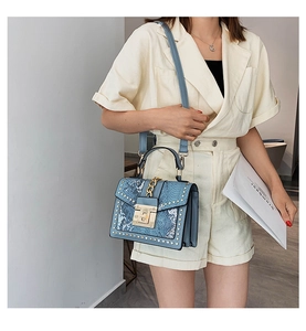 Blue snakeskin pattern leather handbag with gold studs and square buckle on model