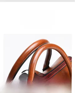 Detail view of brown crocodile texture leather bag with double round handles and stitching