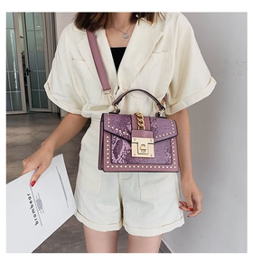 Detail of purple snake-pattern handbag with gold rivets and chain on beige outfit
