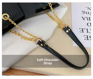 Detail of crocodile embossed leather bag with gold metal chain and soft shoulder strap