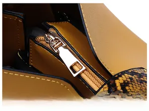 Detail of light gold zipper and yellow lychee leather on a stylish bucket bag