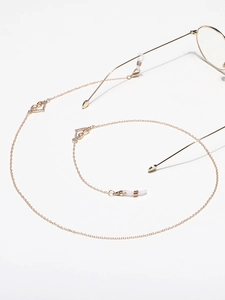 Détail de chaîne à lunettes dorée avec pendentifs cœur en strass et boucles silicone