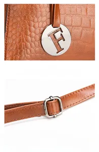 Detail of brown crocodile pattern handbag with metal F pendant and adjustable strap
