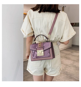 Detail view of purple snakeskin pattern bag with gold studs and chain strap on model