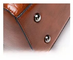 Detailed view of brown leather bag base with anti-slip rivets and durable stitching