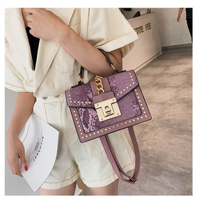Detail of purple snakeskin leather handbag featuring gold studs and metal chain buckle