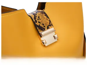 Detail of yellow pebbled leather handbag with gold metal clasp and snakeskin pattern