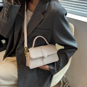 Chic cream white crossbody square bag with gold hardware worn by model in grey suit