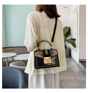 Retro black leather bag with yellow snakeskin print and gold stud details on model