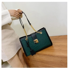 Detail of dark green crocodile texture bag with gold chain strap and metal lock