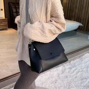 Minimalist black flap crossbody bag with geometric woven wide strap and gold hardware detail