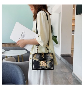 Detailed view of snake print handbag with gold studs and chunky chain strap