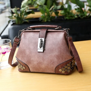 Retro brown leather doctor bag with metal chain lock and vintage rivets on a wooden table