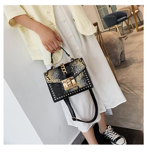 Detail of a black and yellow snake skin leather handbag featuring gold rivet studs
