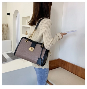 Detailed close-up of crocodile texture leather tote with elegant gold buckle and chain