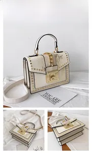 Detail of beige snakeskin textured handbag featuring gold studs and chunky chain accent