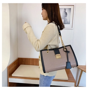 Detail of mocha crocodile pattern tote bag featuring gold buckle and chain strap