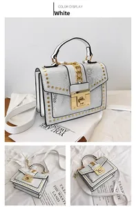 Close-up of white embossed leather handbag with gold chain detail and metallic rivets