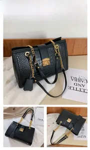 Detail of black crocodile texture tote bag with gold metal lock and chain strap