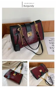 Detail of wine red crocodile embossed tote with golden chain strap and clasp