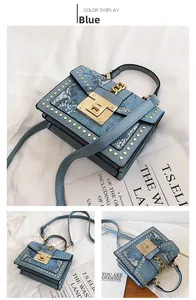 Close-up of light blue snakeskin leather handbag featuring golden round studs and metal clasp