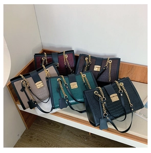 Detail view of five different colors of crocodile pattern bags with gold chain straps