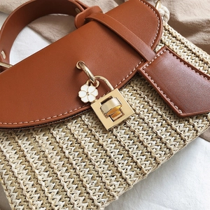Retro summer straw handbag with brown leather flap and floral charm on beige fabric