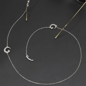 Silver eyewear chain with rhinestone star and moon charms on a dark textured background
