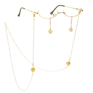 Monture de lunettes dorée avec pendentifs étoiles et chaîne de perles sur fond blanc