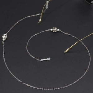 Chaîne de lunettes argentée avec perles et boules de strass sur fond noir