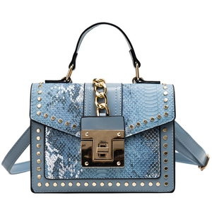 Light blue faux snake leather handbag with gold rivets and chain strap on white background