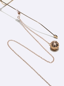 Macro detail of golden metal eyeglass chain with hollow sphere pendant and silicone loop