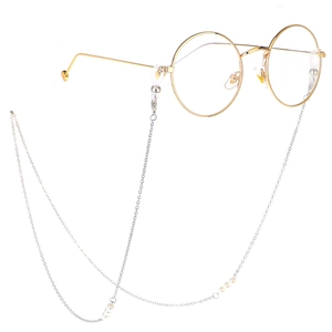 Monture de lunettes ronde en métal doré avec chaîne en perles argentées sur fond blanc