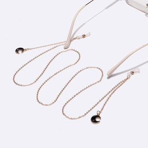 Gold eyeglasses chain with black crescent moon and star charms on white background
