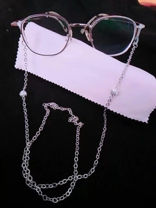 Close-up of silver metal eyewear chain with rhinestones and silicone loops on pink glasses