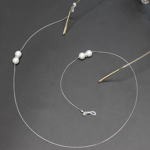 Chaîne de lunettes vintage avec perles blanches et strass sur fond gris foncé