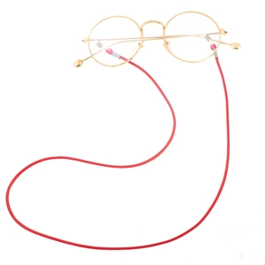 Detail of red braided wax cord eyewear strap attached to gold thin metal round glasses