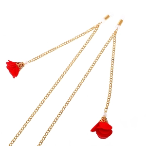 Golden eyewear chain with red fabric flower tassels and white pearl accents on white background