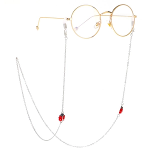 Silver eyewear chain with red ladybug pendants on gold round frame glasses